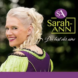 Du bist der eine” von Sarah-ANN – Sängerin im Dirndl mit Lächeln über die Schulter schauend